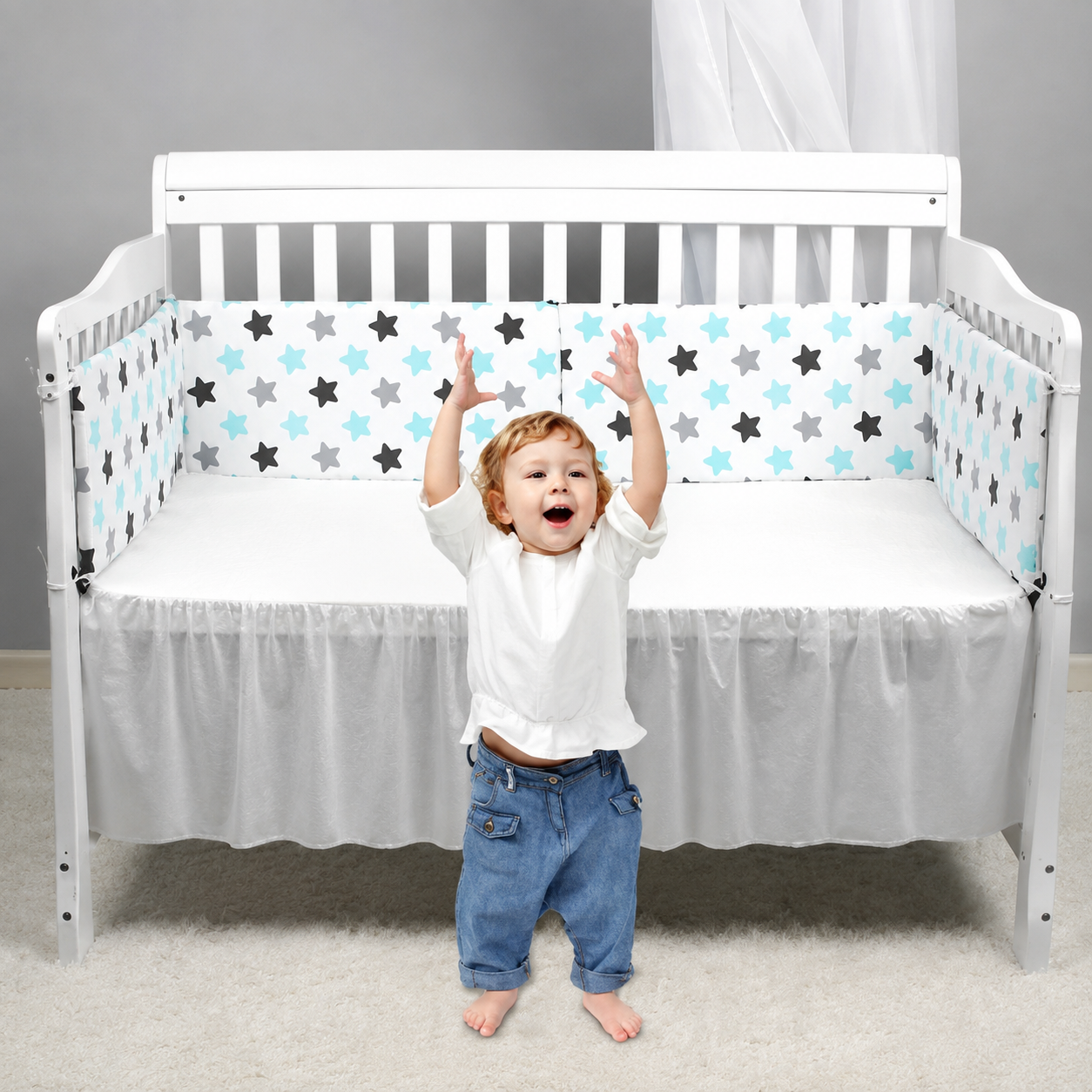 bébé joue à coté de son lit avec tour de lit bébé couleur verte blanche et étoile bleu et noire